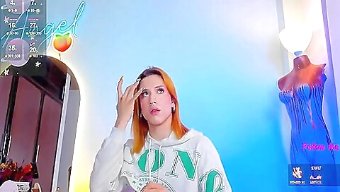 Redheaded woman is on her bed and taking off her clothes